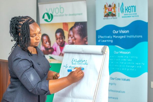 A school leaders in the third cohort of the Effective School Leadership for Junior Schools ESL4JS training taking notes during group discussions during an in person session . 1