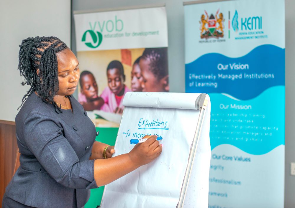 A school leaders in the third cohort of the Effective School Leadership for Junior Schools ESL4JS training taking notes during group discussions during an in person session . 1
