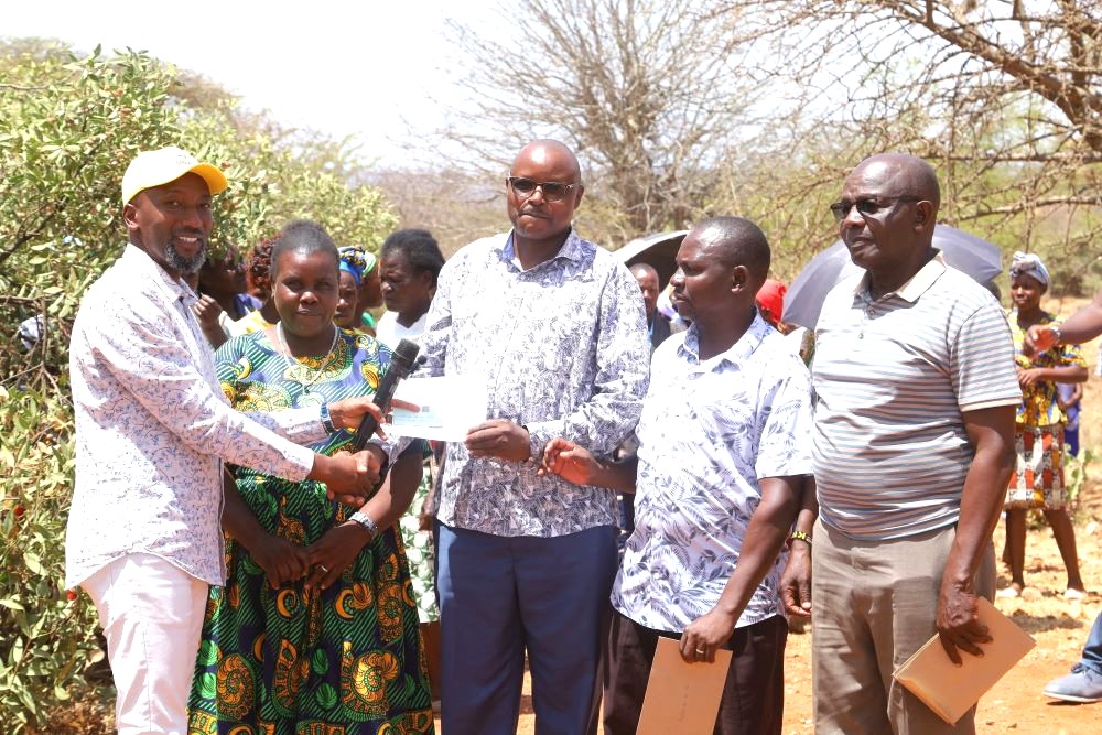 MP Leonard Wa Muthende left issues cheques to day secondary school heads during a Free Day Secondary Education launch at Karerema Market
