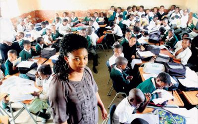 A teacher attending to students in an overcrowded classroom