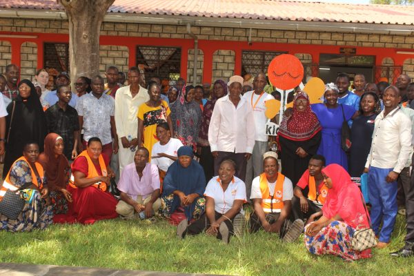 A section of the community members and Kids Care officials led by its director George Baya takes a group photo at Lunga-Lunga sub-county in Kwale County
