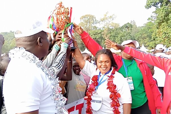 Early Childhood Development Education Director Mdm Martha Odundo (at the centre)awards a trophy to Rift Valley Region officials for emerging overall winners in this year's KPJSSA-SPORTS Championship held in Maseno School. Photo by Peter Amos