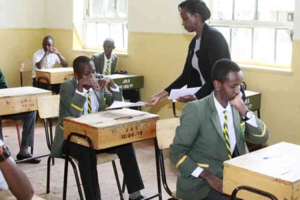 An examiner distributes test papers to candidates. KNEC must honour its contractual obligations without further delay