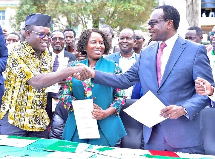 UASU Secretary General Constantine Wasonga (left) shakes hands with Education CS Julius Ogamba after signing the return-to-work deal
