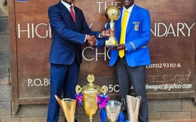 Chief Principal Irungu Nduati receives a trophy from a Highway Senior School student, part of the haul of accolades the institution collected under his six-year tenure