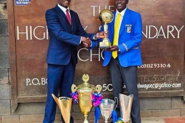 Chief Principal Irungu Nduati receives a trophy from a Highway Senior School student, part of the haul of accolades the institution collected under his six-year tenure