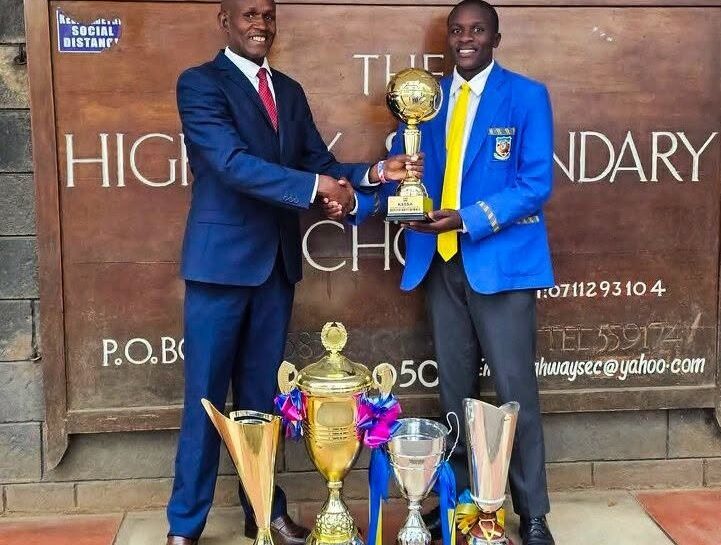Chief Principal Irungu Nduati receives a trophy from a Highway Senior School student, part of the haul of accolades the institution collected under his six-year tenure